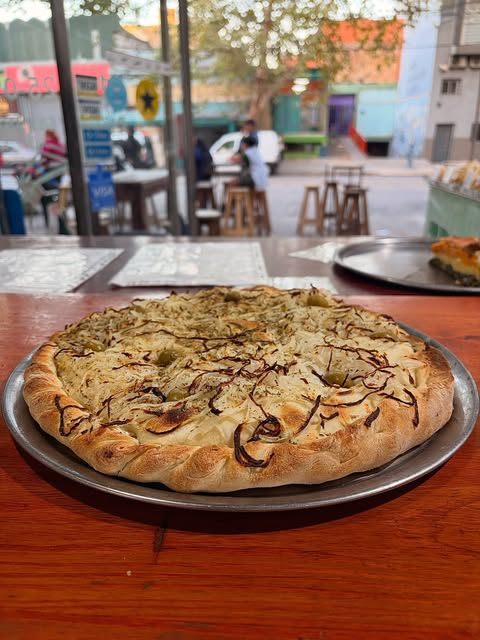 Pizza de cebolla con aceitunas junto a la ventana del local