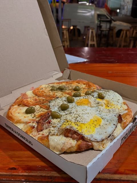 Pizza con huevo frito y aceitunas en caja