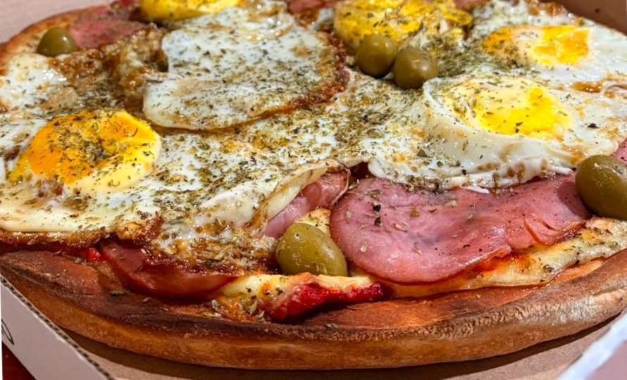 Pizza con jamón, huevo frito y aceitunas