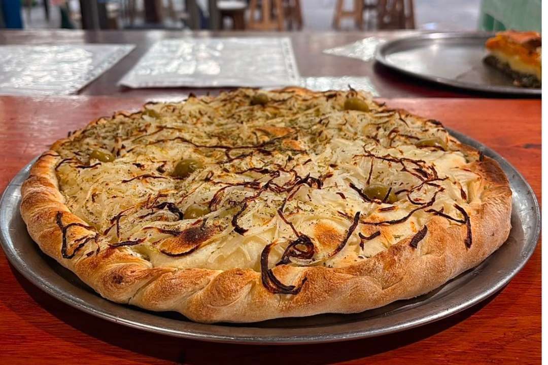 Pizza de cebolla en bandeja sobre la mesa del local