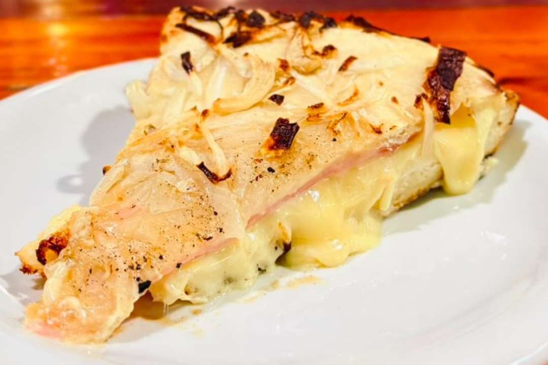 Porción de pizza de cebolla con jamón y queso